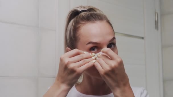 Close up of Woman puts collagen pads under her eyes and looks at the camera - Video