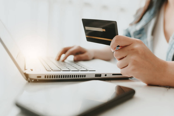 Siyah kredi kartını tutan ve dizüstü bilgisayar kullanan elleri yakın plan çek. Çevrimiçi alışveriş veya ödeme - Fotoğraf, Görsel