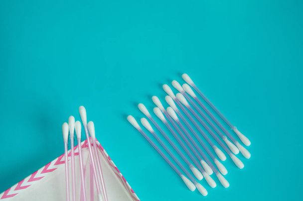 Top view, flat lay, a small group of pink plastic cotton swabs neatly arranged on a mint background, the concept of cleanliness and hygiene. - Photo, Image