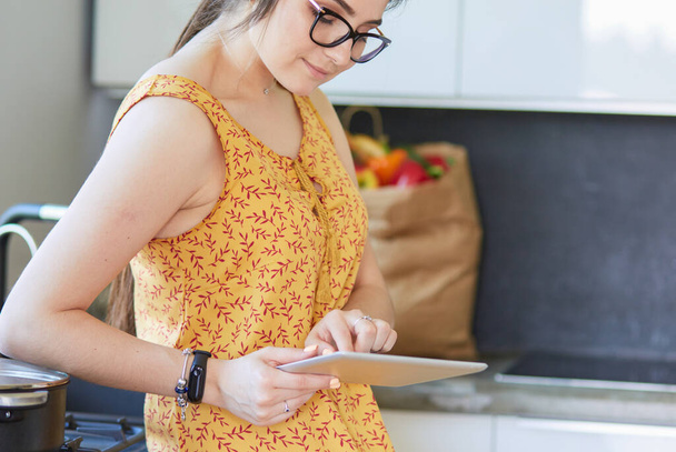beautiful young woman using a digital tablet in the kitchen - Photo, image