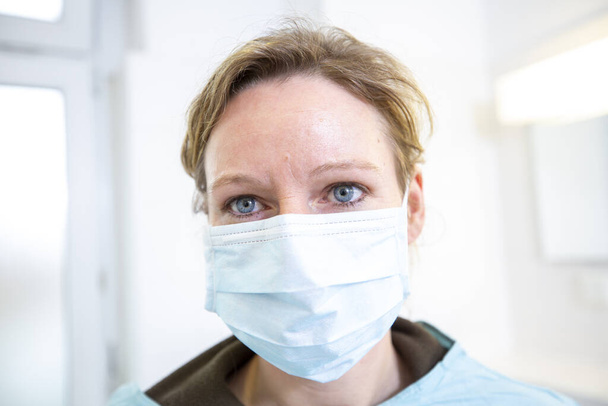 Ženský lékař v plně chráněném lékařském obleku drží náustek - Fotografie, Obrázek