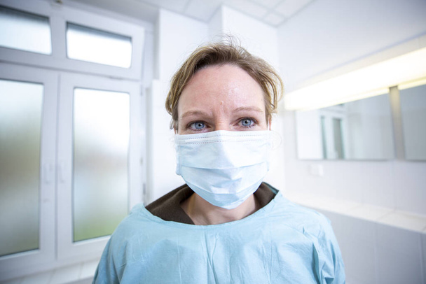 Женщина-врач в полностью защищенном медицинском костюме держит мундштук
 - Фото, изображение
