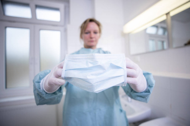 Женщина-врач в полностью защищенном медицинском костюме держит мундштук
 - Фото, изображение