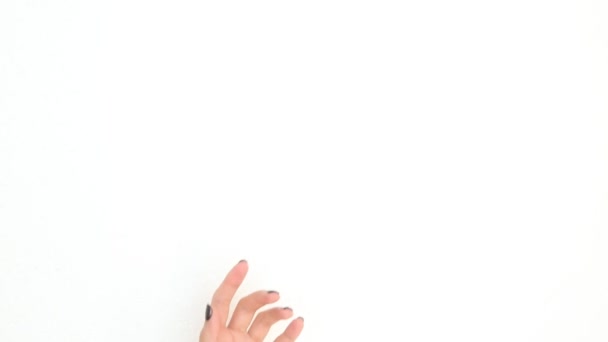 Mooie handen van een jonge vrouw met een zwarte manicure in beweging brengen crème aan op haar handen en wrijven. Op witte achtergrond - Video