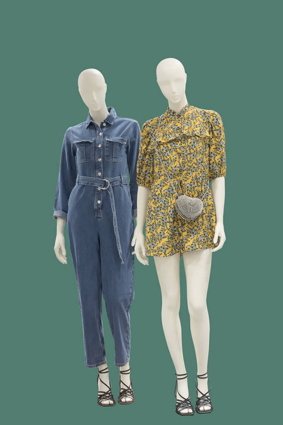 Two full-length female mannequins dressed in fashionable clothes, isolated on green background. No brand names or copyright objects. - Foto, Bild