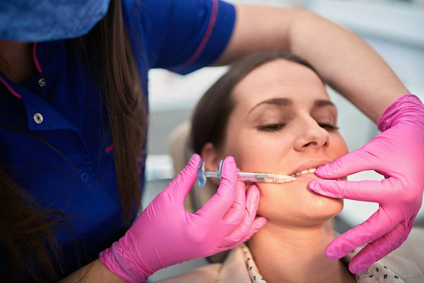 Doctor enlarges lower lip of the female client   - Φωτογραφία, εικόνα