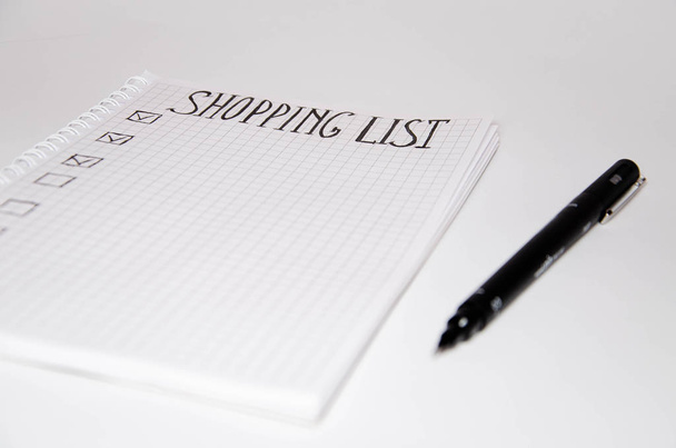 Lista de compras. Caderno quadrado com caneta preta sobre fundo branco. Grave ideias, notas, planos, tarefas. A lista inclui pão, leite, bananas. Espase de cópia
 - Foto, Imagem