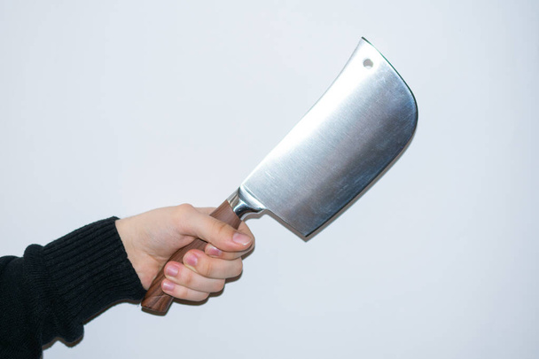 Caucasian hand on black sweater holding a kitchen axe, isolated on a white background, pointing to the right - Fotó, kép