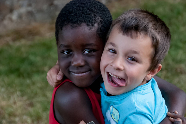 Beyaz çocuk ve siyah çocuk sarılıyor. - Fotoğraf, Görsel