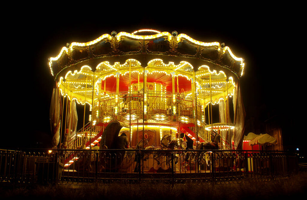 Carrousel illuminé la nuit dans une fête foraine rétro. Parc d'attractions Vintage
. - Photo, image
