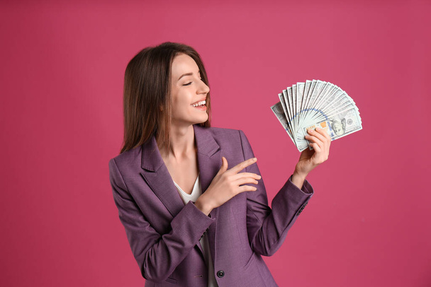 Happy young woman with cash money on pink background - Фото, изображение