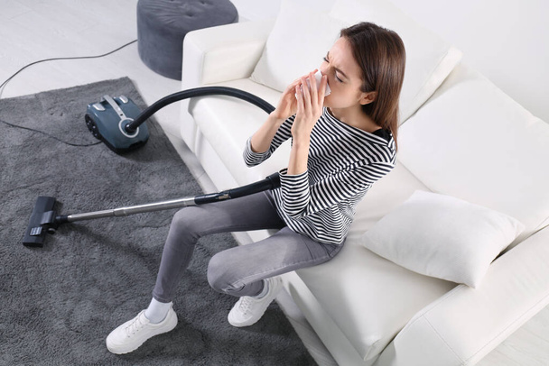 Young woman suffering from dust allergy while vacuuming house - Foto, Imagem
