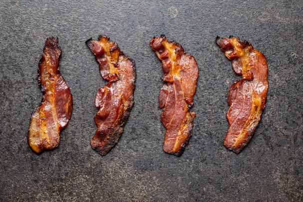 Fried bacon. Sliced roasted bacon on old kitchen table. Top view. - Φωτογραφία, εικόνα