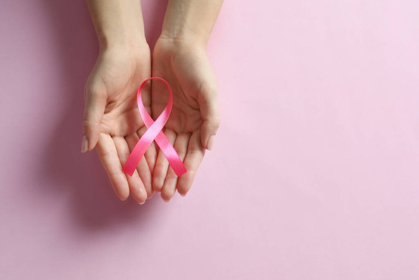 Woman holding pink ribbon on color background, top view with space for text. Breast cancer awareness - Foto, Imagem