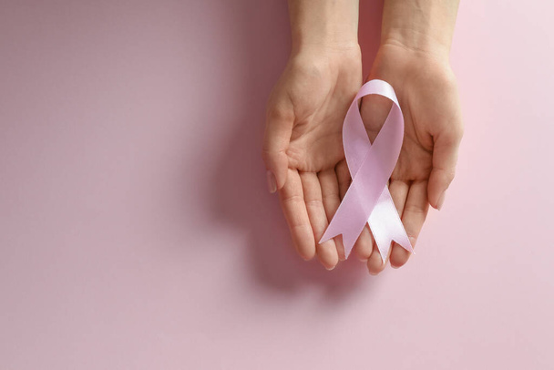 Woman holding pink ribbon on color background, top view with space for text. Breast cancer awareness - Zdjęcie, obraz
