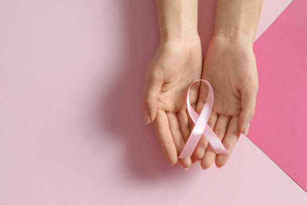 Woman holding pink ribbon on color background, top view with space for text. Breast cancer awareness - Фото, изображение
