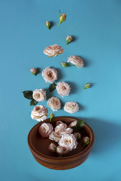 Creative layout of wooden tableware with roses on a blue background. Levitation of the flower. The magic and tenderness. Beautiful levitation. Flatley. Vertical orientation. Happy mother's day - 写真・画像