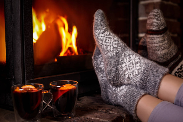 People with mulled wine resting near fireplace indoors, closeup - Foto, Imagen