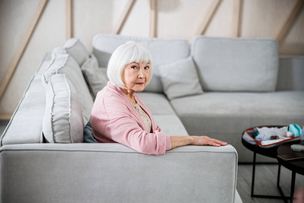 Senior woman sitting on comfortable couch at home - Foto, Imagen