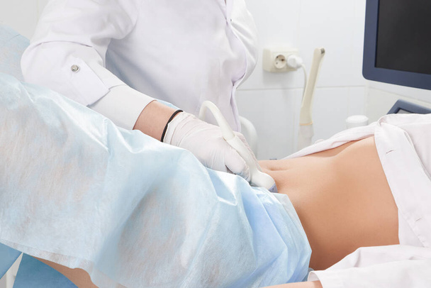 Gewassen beeld van de vrouw bij gynaecologen doen echografie scan van het onderste deel van de buik - Foto, afbeelding