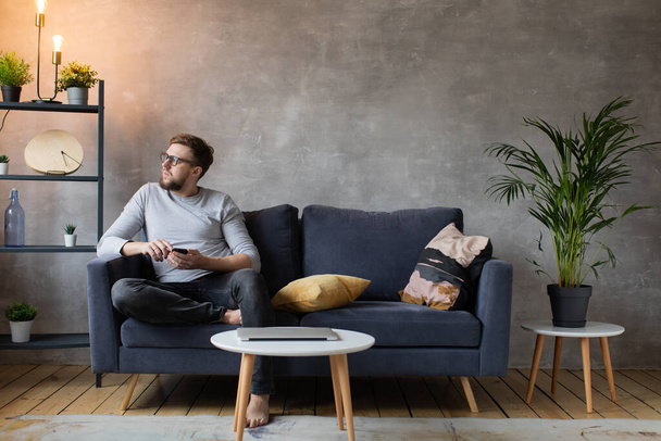 Young man in glasses angry talking on the phone sitting on the couch. Young businessman. - Photo, image