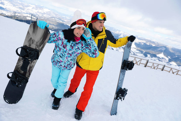 Υπέροχο ζευγάρι με snowboards στο λόφο. Χειμερινές διακοπές - Φωτογραφία, εικόνα