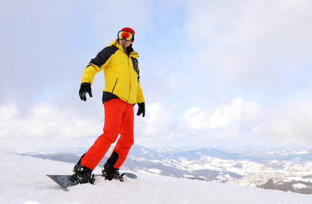 Male snowboarder on snowy hill. Winter vacation - Фото, изображение