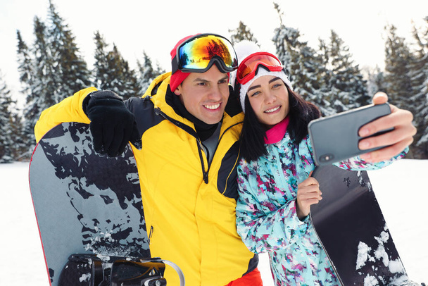 Couple taking selfie on snowy hill. Winter vacation - Фото, изображение