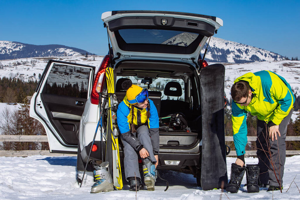 homem e mulher vestir-se em equipamento de esqui perto de carro SUV. montanhas no fundo - Foto, Imagem