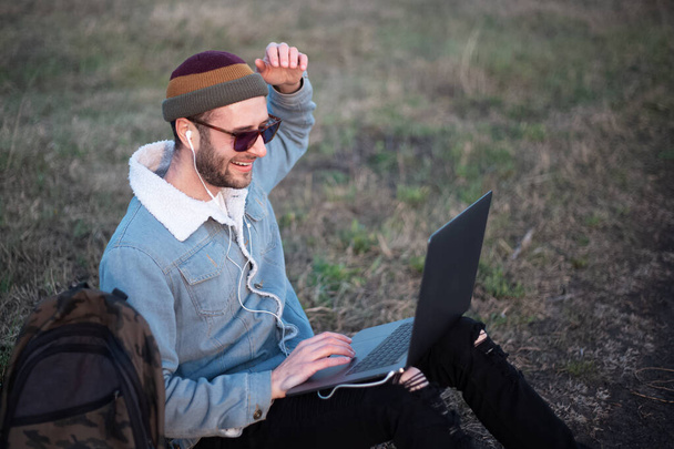 Portré fiatal hipster férfi használó laptop szabadban. - Fotó, kép