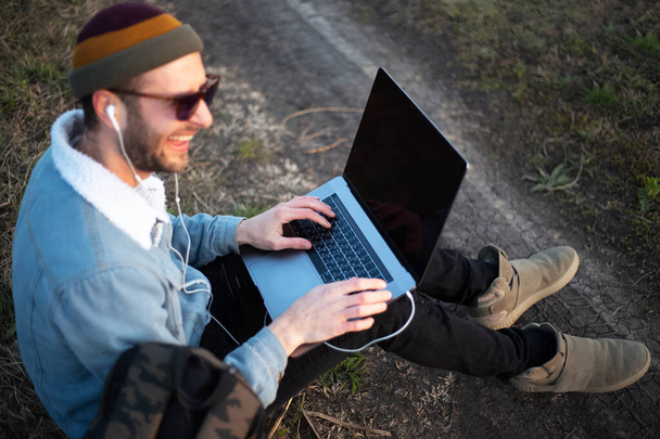 Retrato de jovem hipster homem usando laptop ao ar livre
. - Foto, Imagem