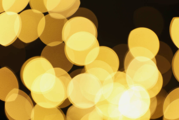 Blurred view of beautiful lights on black background. Bokeh effect - 写真・画像