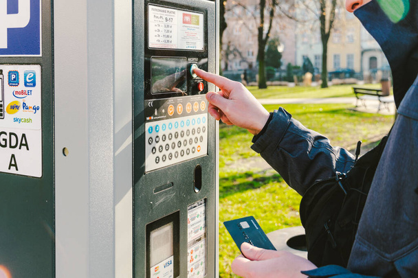 hombre paga por aparcar con una tarjeta de crédito con tecnología NFS. Pago fácil. Proceso de pago en terminal de estacionamiento de máquinas. Pago por estacionamiento en la ciudad de Gdansk, Polonia 8 de febrero de 2020
. - Foto, Imagen