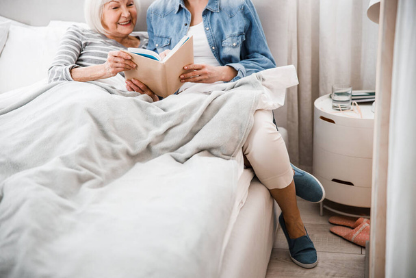 Smiling old woman reading book with adult granddaughter - Fotografie, Obrázek
