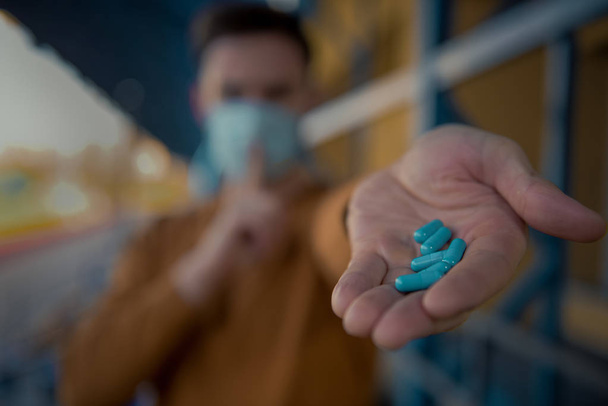 Männer in chirurgischer Maske mit einer Flasche medizinischer Pillen gegen Coronavirus in China, Apothekenarzt mit Tabletten in der Hand zur Behandlung epidemischer Krankheiten, Patient in Maske allein im Stadion - Foto, Bild