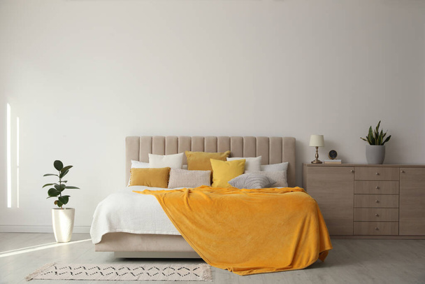 Stylish bedroom interior with soft yellow pillows and blanket - Foto, immagini
