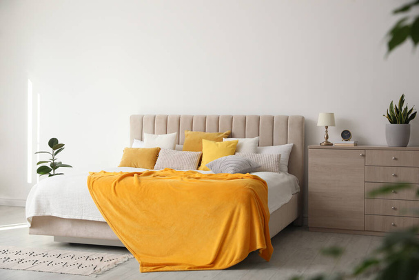 Stylish bedroom interior with soft yellow pillows and blanket - Foto, imagen