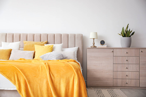 Stylish bedroom interior with soft yellow pillows and blanket - Foto, Bild