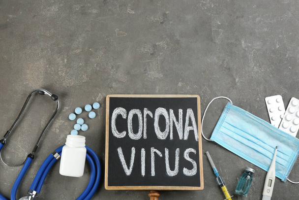 Chalkboard with words CORONA VIRUS, stethoscope and medicines on grey stone background, flat lay. Space for text - Фото, изображение