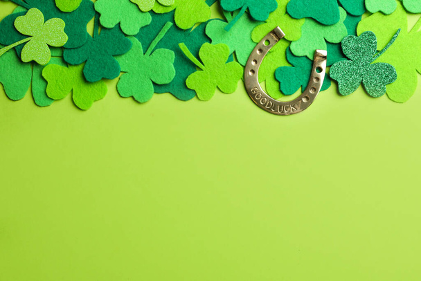 Flat lay composition with clover leaves and horseshoe on green background, space for text. St. Patrick's day - Фото, зображення