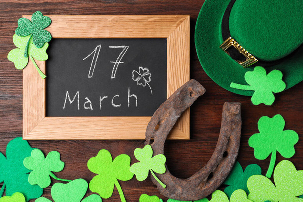 Flat lay composition with horseshoe and chalkboard on wooden background. St. Patrick's Day celebration - Фото, зображення