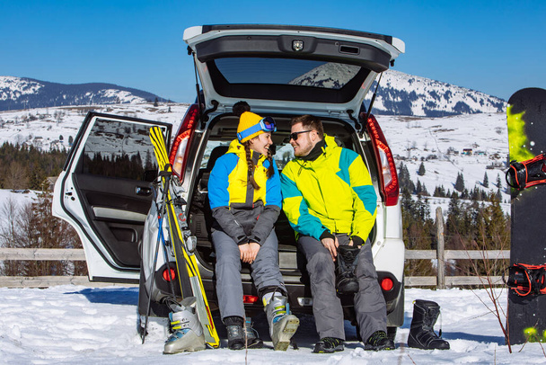 hombre y mujer vestirse con equipo de esquí cerca de coche todoterreno. montañas en el fondo - Foto, Imagen
