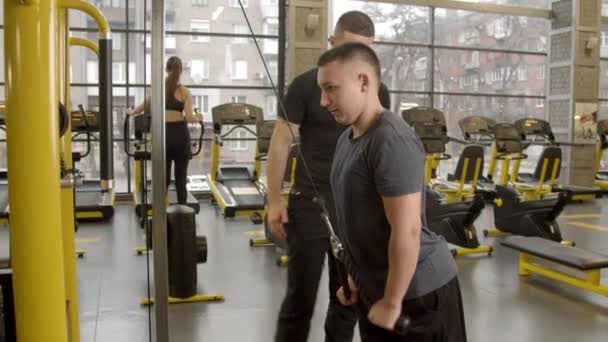 Zdravotně postižený mladý muž s instruktorem cvičení v tělocvičně - Záběry, video