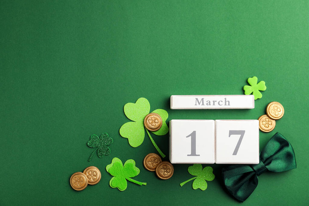 Flat lay composition with wooden block calendar on green background, space for text. St. Patrick's Day celebration - Foto, Bild