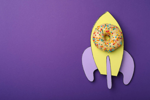 Rocket made with donut and paper on purple background, top view. Space for text - Фото, зображення