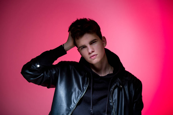 Cute brutal man in black leather jacket model style. Portrait of a handsome guy on pink studio background. Man In Black Jacket. Young Fashion Man In Leather Jacket on a pink background - Photo, Image