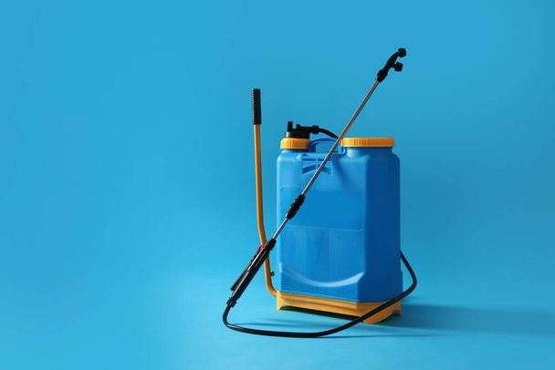 Pulverizador de inseticida manual em fundo azul, espaço para texto. Controlo de pragas
 - Foto, Imagem