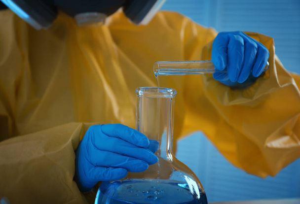 化学保護訴訟の科学者は研究室でフラスコに試薬を注ぐ,閉鎖.ウイルス研究 - 写真・画像