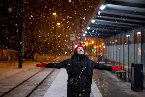 Kar seyreden bir kadın kış gecesi tramvay istasyonunda dikiliyor. - Fotoğraf, Görsel