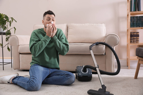 Man with vacuum cleaner suffering from dust allergy at home - Photo, image
